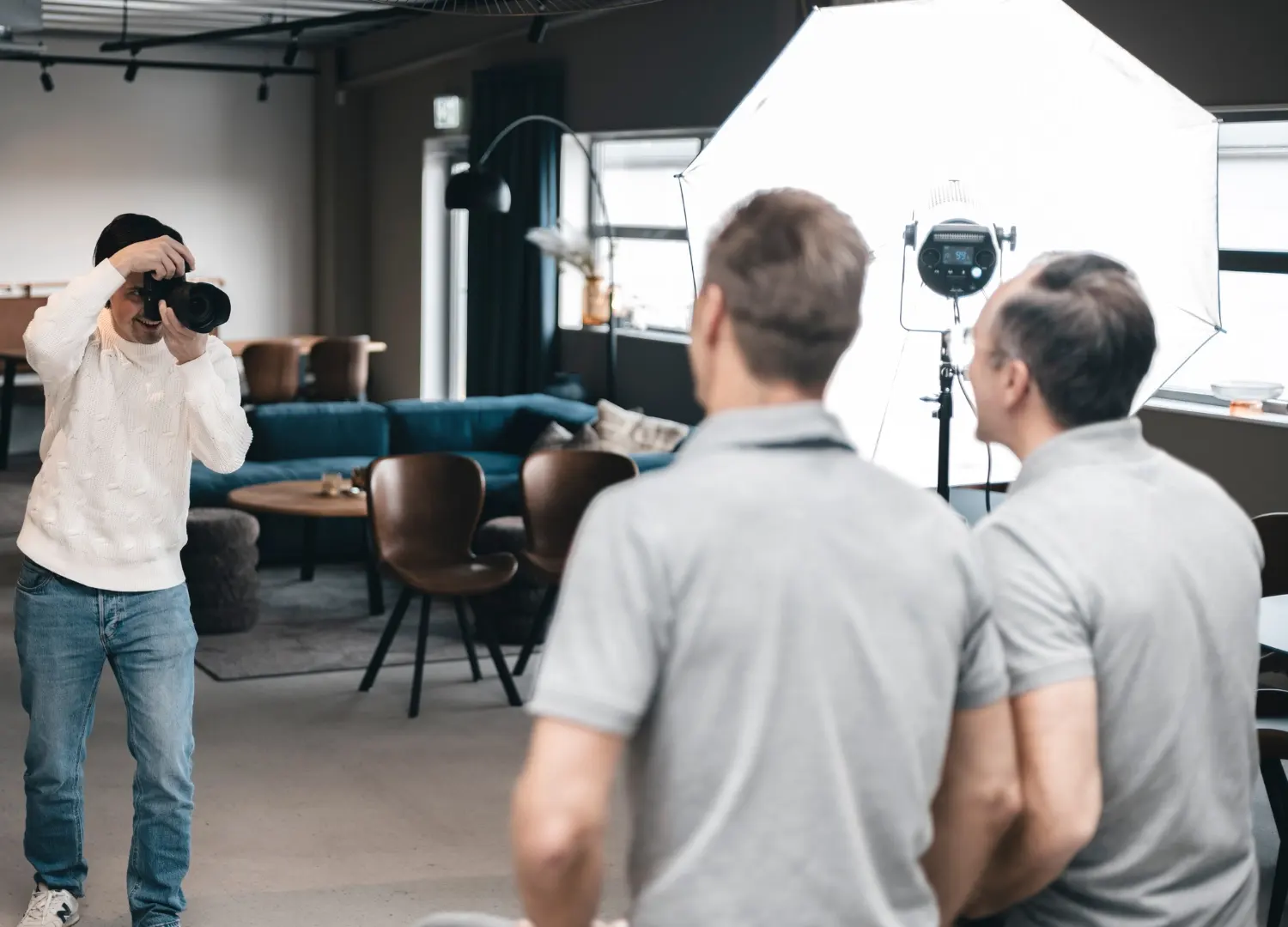 En man tar en bild med en kamera i en studio, omgiven av professionell belysning och utrustning.
